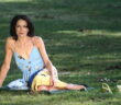 A woman in a blue and yellow dress sitting on the grass.